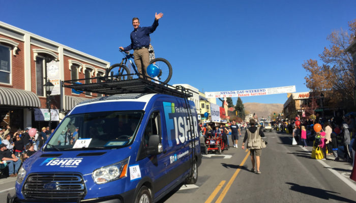 Jared Fisher riding on top of the van in the Fisher for Nevada parade